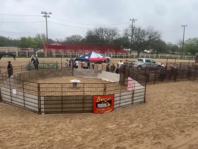 Overhead view of the octagonal hog-catch pen in the arena, Texas-flag tent and red bleachers behind.